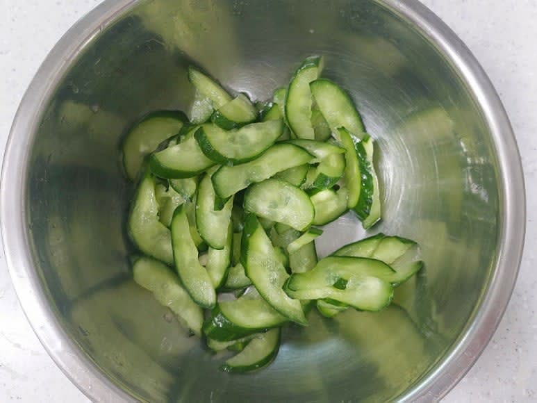 오이는 굵은소금으로 문질러 세척 후 반 갈라 0.4cm 두께로 어슷 썬 뒤 굵은소금 1/2스푼을 넣어 10분 절인 뒤 물에 씻지 않고 그대로 물기를 짜 주세요.