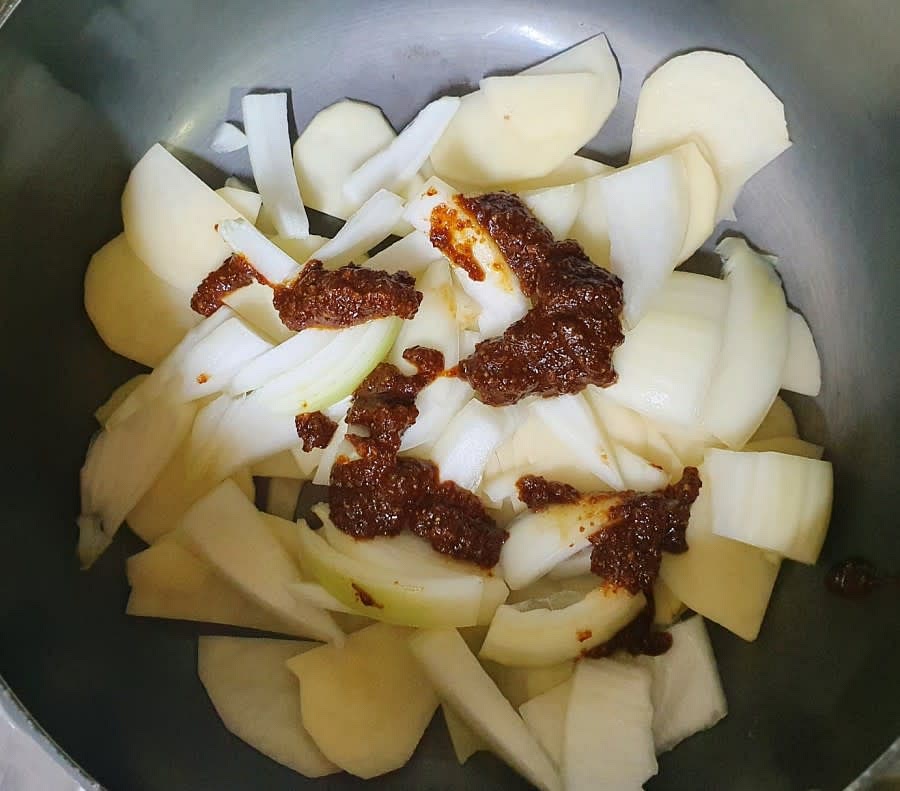 냄비에 썰어놓은 감자와 양파를 깔고 그 위에 만들어 놓은 양념장 반정도를 넣어주세요.