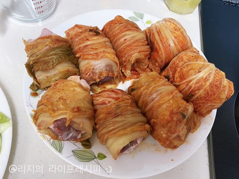 넓은 배추김치 한장에 삼겹살을 올려주고 돌돌 말아주고 잎사귀 끝나는 부분이 밑으로 오도록 놓아주세요