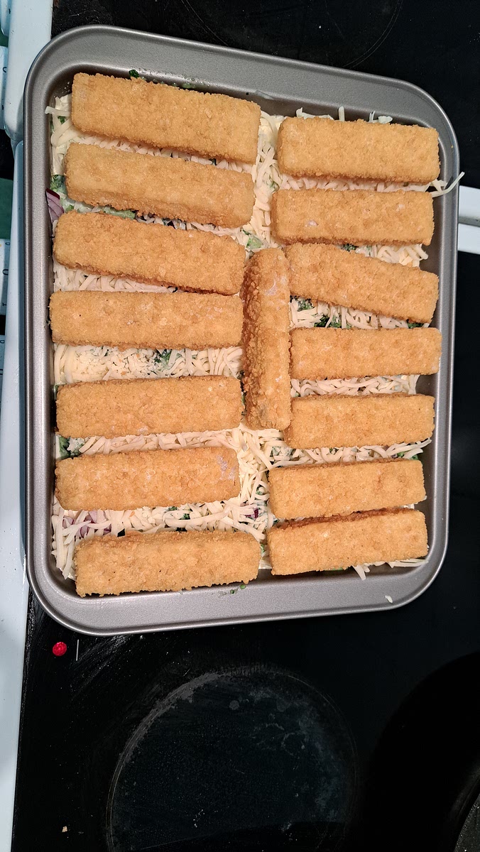 Käse über den Auflauf geben und die Fischstäbchen darauf verteilen