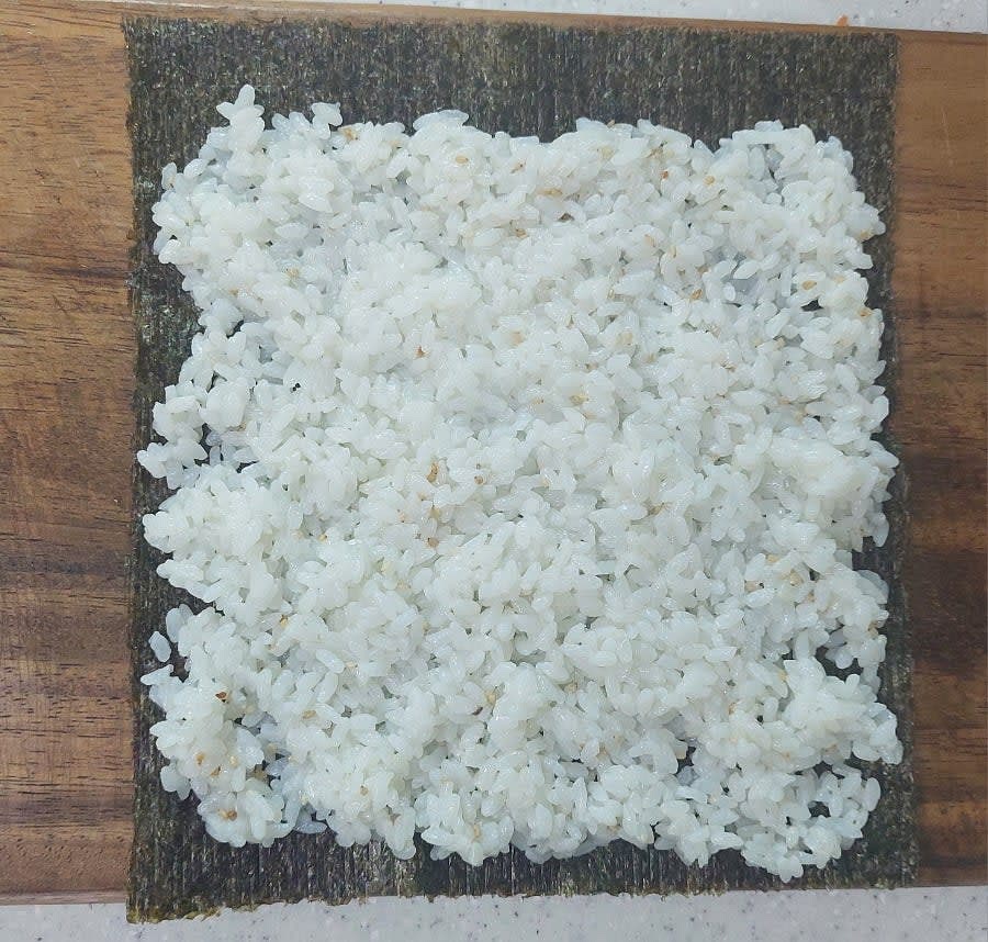 김밥김의 거친 면이 위로 향하도록 김을 깔고 그 위에 밥을 올려 펴 줍니다.