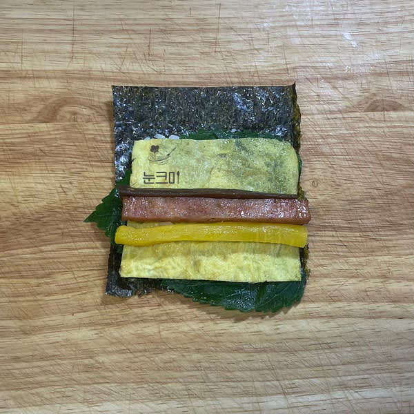 깻잎과 계란부침, 단무지, 스팸, 우엉을 올려줍니다.
