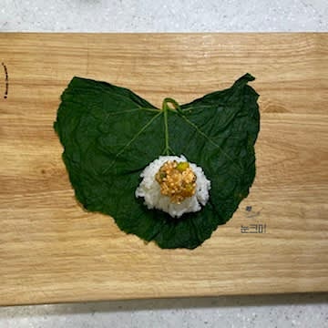 호박잎의 물기를 살짝 짜준 뒤 도마 위에 펼쳐 놓고 밥 1큰술과 두부강된장을 올려줍니다.