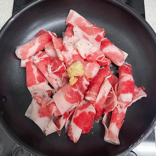 중약불에 달군 팬에 대패삼겹살을 넣어주고 다진마늘 0.5큰술과 후추를 톡톡 뿌려줍니다.