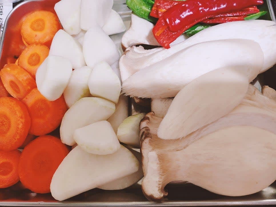 무와 당근은 먹기 좋은 크기로 자른 후 모서리를 둥글게 다듬어주세요. 새송이버섯은 편으로 썰고 고추는 씨를 제거하고 길게 잘라 주세요. 양파는 큼직하게 썰어주세요