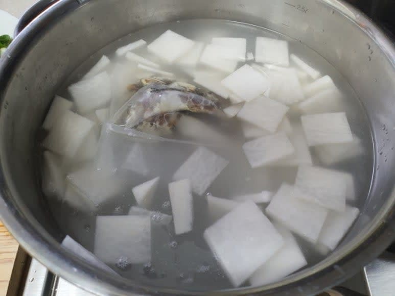 육수용 멸치는 다시 팩에 담고, 다시마, 다진 마늘, 나박 썰기한 무와 함께 물에 넣고 끓인다.