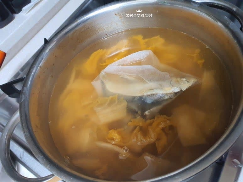 볶은 김치에 물을 붓고 육수 재료는 다시팩에 담아 넣어주고 마늘 1큰술을 넣어줍니다.