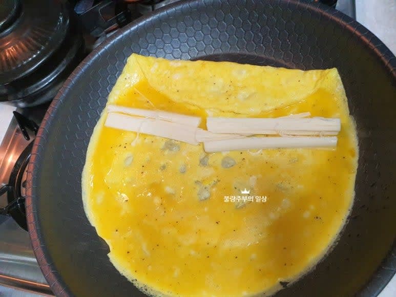 계란물을 팬에 얇게 펼쳐 익힌 후 스트링치즈를 올리고 말아줍니다. 이 과정을 반복하여 계란말이를 만듭니다.