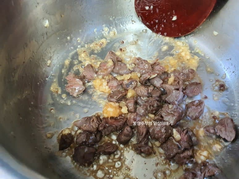 썰어 놓은 소고기를 참기름 2큰술을 넣고 냄비에 볶아 줍니다. 고기 겉이 어느 정도 익으면 다진마늘 0.5큰술을 넣고 잘 볶아 줍니다.