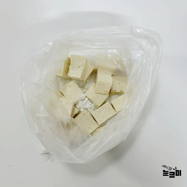 봉지에 전분 2큰술과 두부를 넣고 흔들어 겉면에 전분이 골고루 묻도록 합니다.