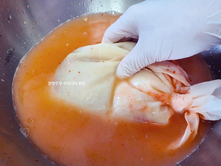 면포나 삼베 주머니 등에 갈아둔 양념 재료와 불려둔 고춧가루를 넣고 생수 1.5리터를 부은 후 양념 재료들이 잘 우러나올 수 있게 손으로 조물조물 눌러 줍니다.