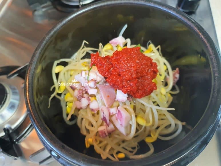 2개의 뚝배기에 데친 콩나물을 나눠서 넣고 오징어와 다대기 1큰술을 올리고 육수 2컵과 생수 1컵을 부어 끓여줍니다.