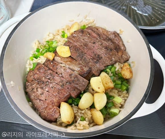 밥이 완성되면 뚜껑을 열고 쪽파를 듬뿍 뿌린 뒤, 잘라둔 채끝스테이크와 통마늘을 얹은 뒤에 뚜껑을 닫고 10분간 뜸들여주세요