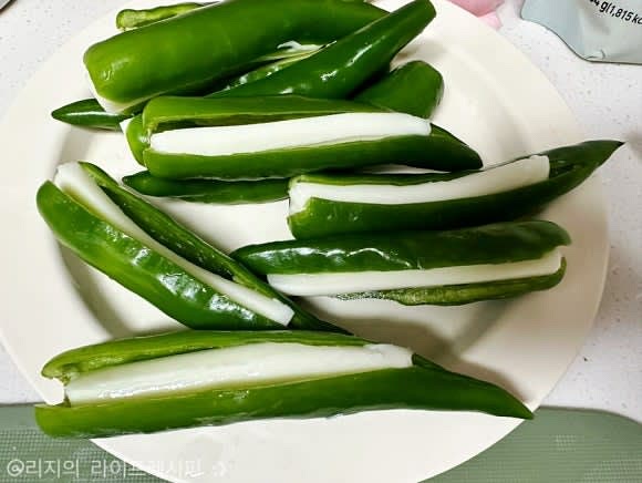 오이고추를 반으로 갈라준 뒤 속에 있는 씨를 살살 손으로 빼내주세요. 스트링치즈는 반을 갈라 준비해주세요