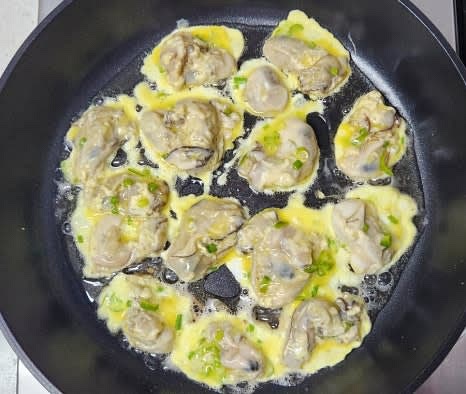 팬에 식용유를 넉넉히 두르고, 중불로 예열한 후, 굴을 하나씩 올려줍니다. 이때 청양고추와 쪽파가 고루 올라가도록 합니다.