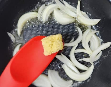 팬에 버터 1조각을 넣고 중불에서 녹인 후, 양파와 다진마늘 1큰술을 넣고 볶아줍니다.