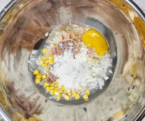 볼에 다진 양파, 콘옥수수 3 큰술, 참치 3 큰술, 계란 1개, 밀가루 3 큰술을 넣습니다.