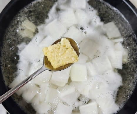 육수가 우러나면 육수팩을 제거하고, 준비한 무를 넣습니다. 다진 마늘 1 큰술도 함께 넣고 중강불에서 끓입니다.