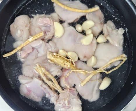 닭이 잠길 정도로 다시 물을 붓고, 통마늘 10개와 황기 5~6조각을 넣어 센 불에서 끓입니다.