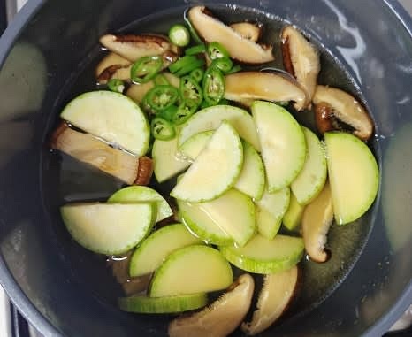 10분 후 육수팩을 꺼내고, 육수에 표고버섯, 청양고추, 애호박을 넣고 센 불에서 끓입니다.