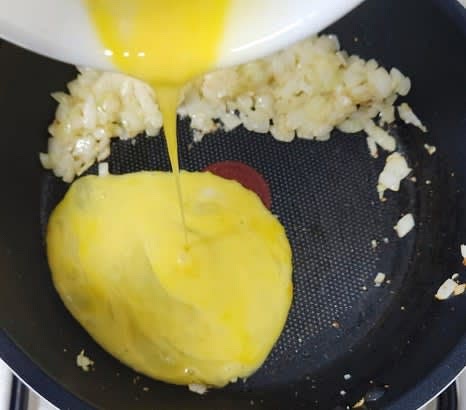 양파를 팬 한쪽으로 밀고, 풀어놓은 계란을 부어 스크램블합니다.