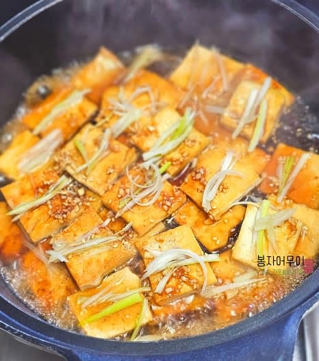 노릇하게 구워진 두부에 물 반컵을 부어주고 양념장을 골고루 뿌려줍니다. 대파도 위에 얹어줍니다.