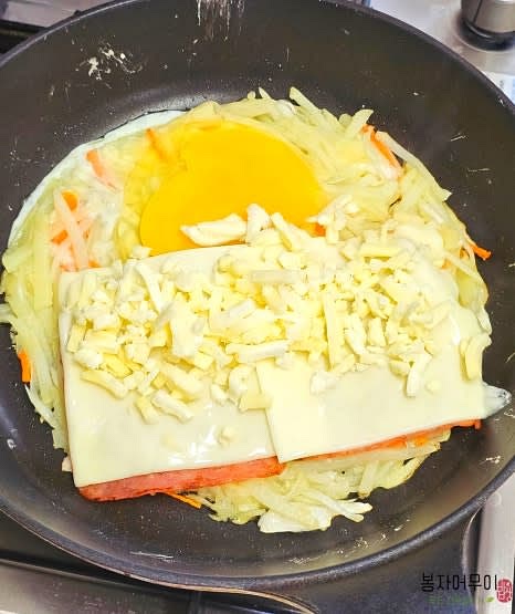잠시 뚜껑을 덮어 익히다가 연기가 피어오르면 뚜껑을 열고 햄, 치즈, 계란, 모짜렐라 치즈를 올립니다.