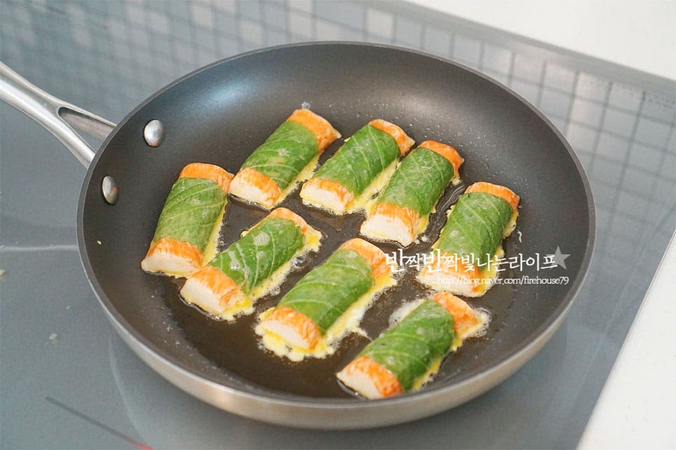 달군 팬에 식용유 넉넉히 두르고 계란 옷 입혀서 하나씩 올려줍니다. 이음새 부분이 바닥에 닿아 먼저 익도록 해주면 풀리지 않게 모양을 낼 수 있습니다. 계란이 반숙으로 익으면 뒤집어 앞뒤로 노릇하게 구워줍니다. 타지 않도록 중약 불로 색을 내어 구워주세요. 향긋한 깻잎 맛살전은 고소한 감칠맛이 느껴지는 게 실패할 수 없는 맛이기도 하죠. 크래미 요리 중에서도 간단한 레시피로 손쉽게 요리할 수 있답니다. 영상도 같이 담았어요. 크래미를 깻잎으로 감싸 부침가루로 이음새를 고정하여 모양내고 달걀물을 입혀 노릇하게 구우면 완성입니다. 초간단 맛있는 요리에요. 크래미 깻잎전 만들기 맛있게 요리해드세요. 끄읕 !