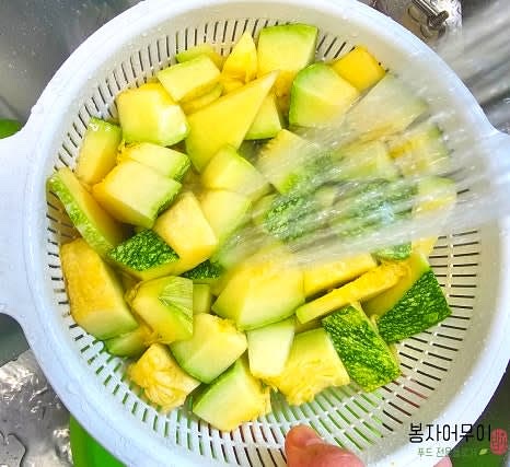 채반에 둥근 호박을 넣고 흐르는 물에 헹구어 손질합니다.