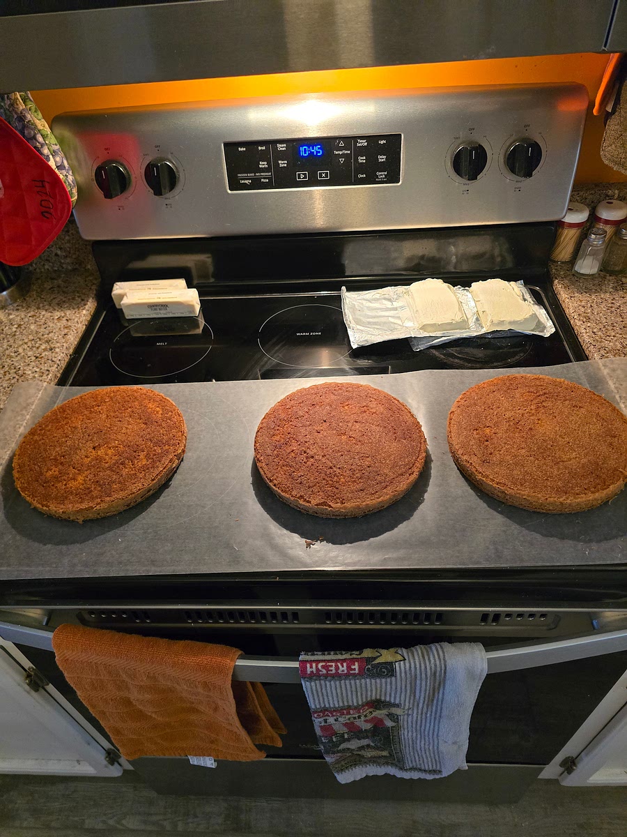 Once done, place pans out and let cool for additional 10 minutes. Once cool to touch, place cakes on a sheet of wax paper long enough for all three. Flip cakes out of pans onto wax paper and dispose of existing wax paper on cake bottoms. Proceed to make cream cheese frosting.