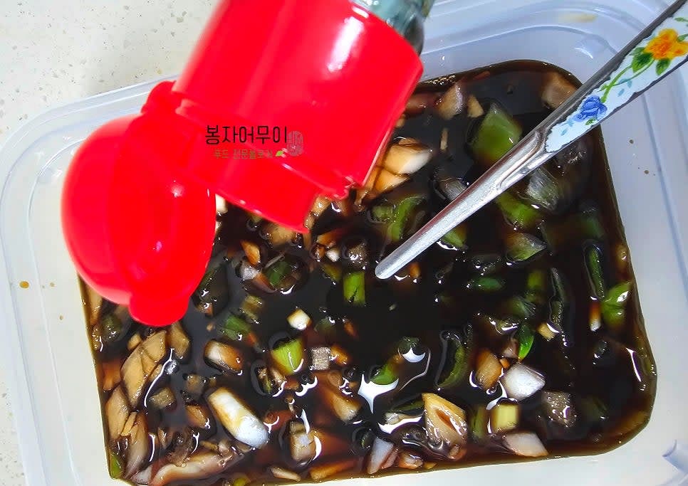 콩나물 비빔밥 양념장을 만듭니다. 간장 1/2컵, 물엿 2스푼, 참기름 1스푼, 다진 마늘 2개를 섞고, 잘게 다진 양파 1/4개와 대파 초록색 부분 1/2개를 추가합니다. 깨소금을 뿌려 완성합니다.