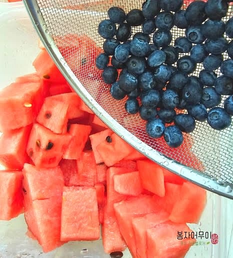 자른 수박과 블루베리를 큰 통에 담습니다.