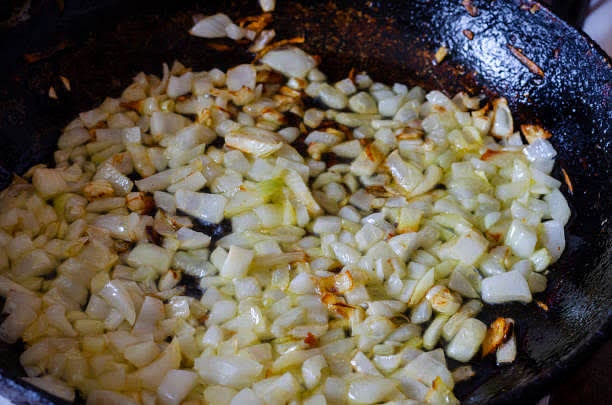add the onions to a wok first and cook them until softened, then add the minced garlic towards the end of cooking as garlic burns much faster than onions and needs less cooking time to achieve its full flavor