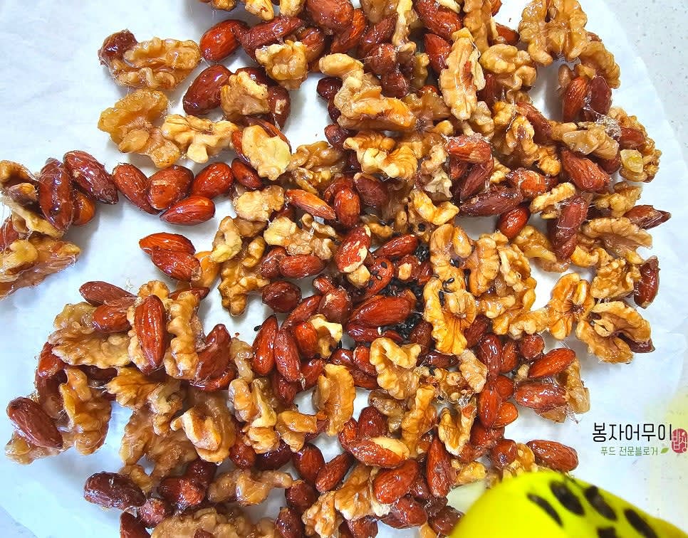버무린 견과류를 종이 위에 펼쳐 식힌 후 흑임자를 뿌려 마무리합니다.