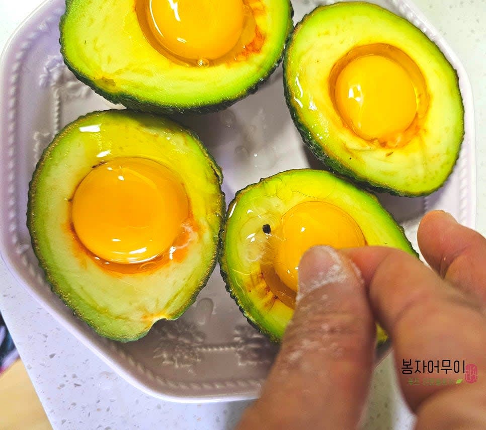 아보카도의 속에 계란 4개를 한 개씩 넣고, 올리브오일을 약간 뿌린 후 맛소금, 후추, 파슬리가루를 골고루 뿌려줍니다.