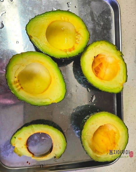 먼저 아보카도 2개를 준비해 계란을 넣을 공간을 만들어주세요. 아보카도의 씨를 제거하고 껍질을 벗기지 않은 상태로 속을 파내어 계란이 들어갈 자리를 만듭니다.