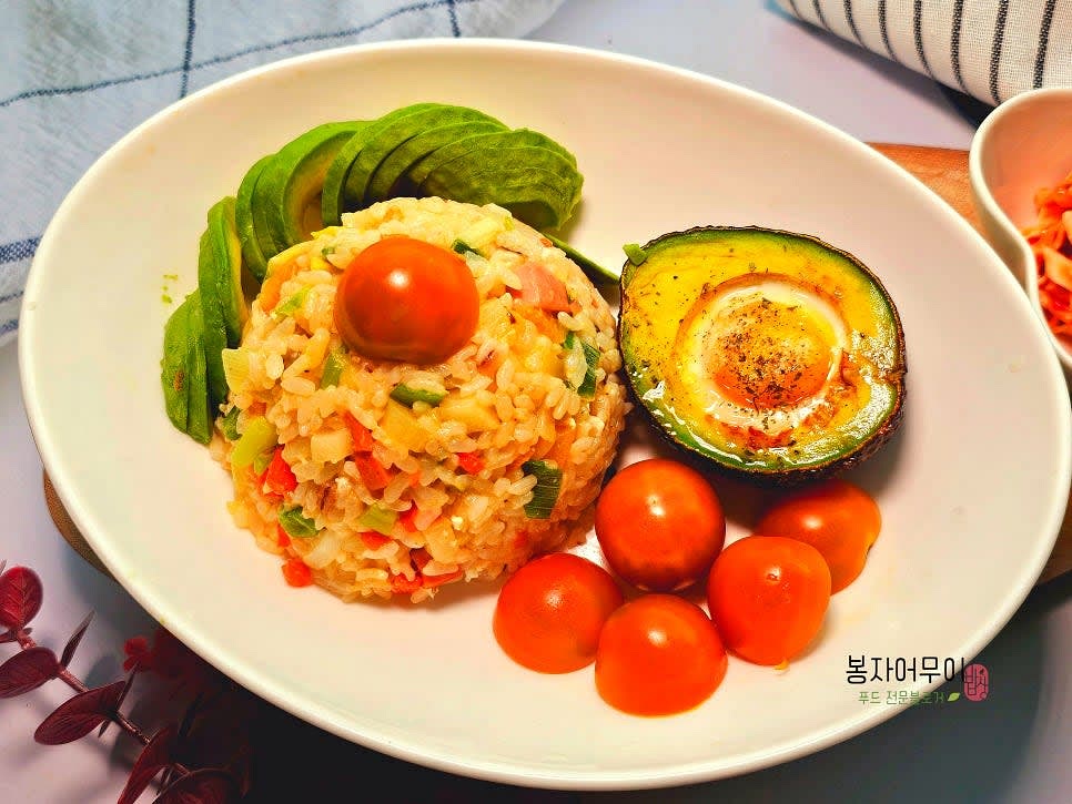 그릇에 볶음밥을 담고, 계란구이를 얹어줍니다. 옆에 방울토마토와 아보카도 슬라이스, 양배추 샐러드를 곁들여 장식합니다.