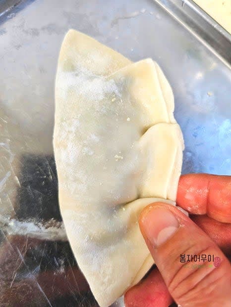 만두피에 만두소를 넣고 접착 부위에 물을 발라 만두를 접어줍니다.