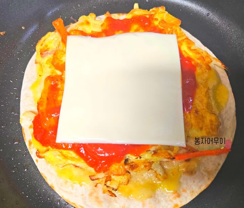 또띠아 위에 부친 계란을 얹고 토마토소스를 바른 후 치즈를 올린다.