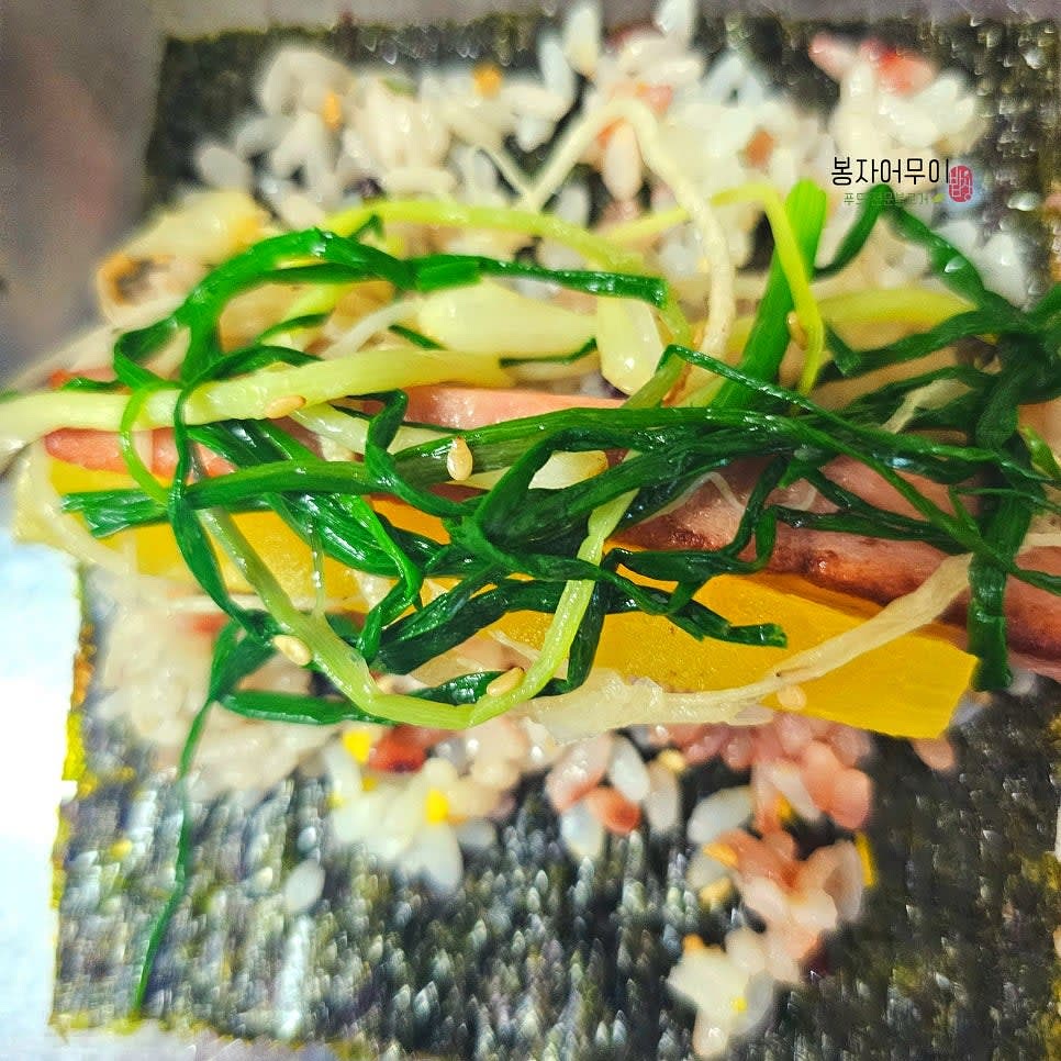 달래, 단무지, 햄을 밥 위에 올린 후 돌돌 말아줍니다.