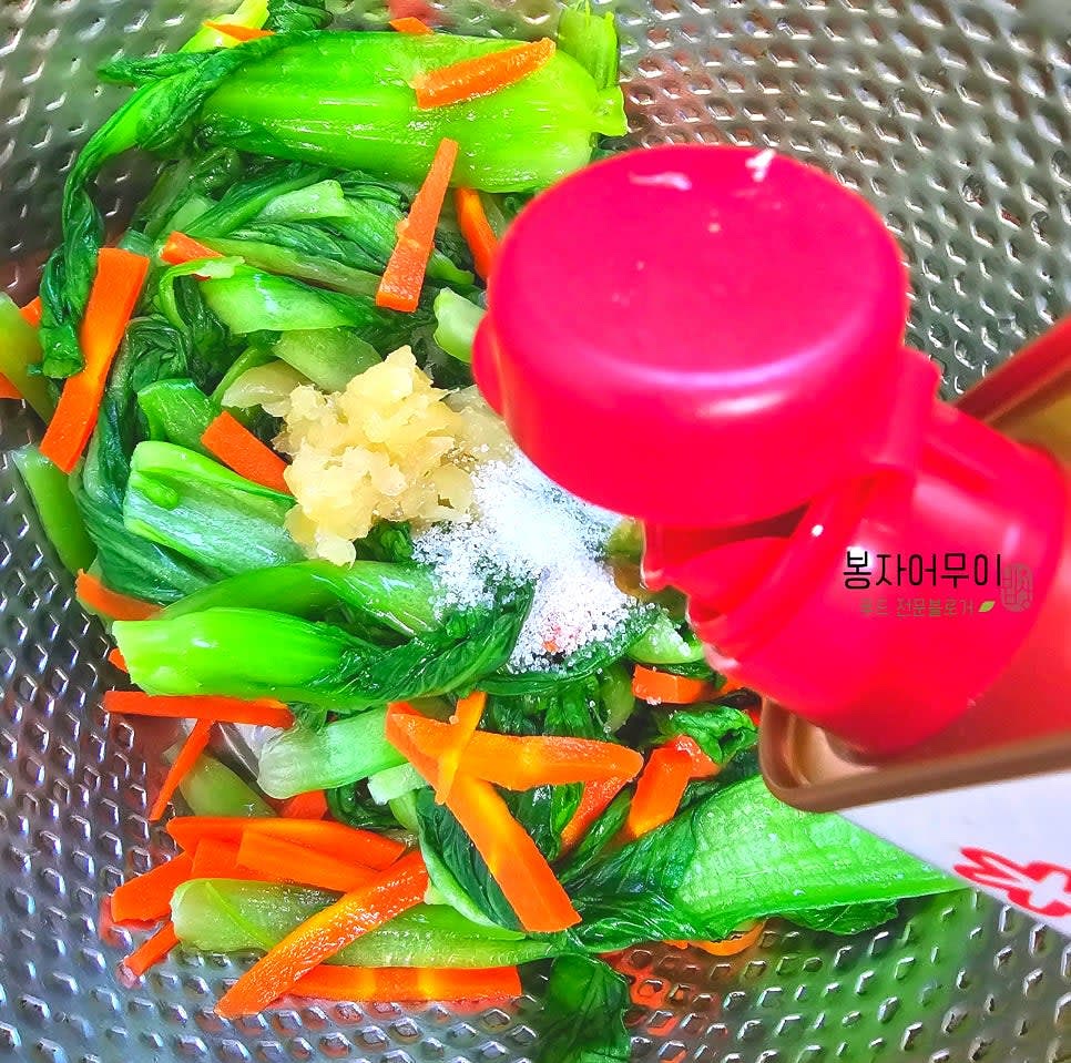 큰 볼에 청경채와 당근을 넣고 다진 마늘, 소금 반 스푼, 참기름 1스푼을 넣어 섞습니다.