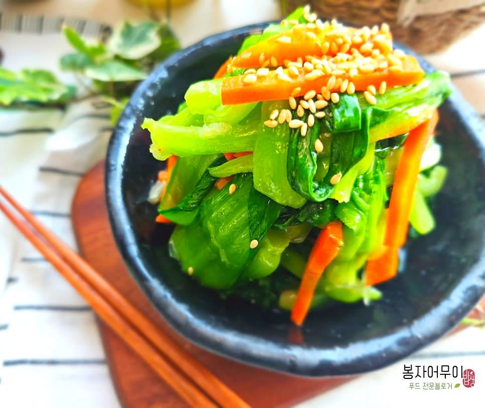 깨소금을 뿌려 완성된 청경채 나물 무침을 접시에 담아냅니다.