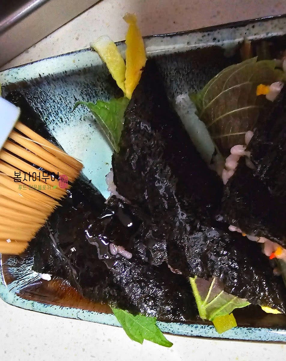 접은 김밥에 참기름을 발라주고 깨소금을 뿌려 완성합니다.