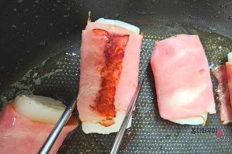 프라이팬에 베이컨 떡말이를 올리고 중불로 앞뒤를 노릇하게 구워줍니다. 베이컨이 고르게 익을 때까지 구워줍니다.