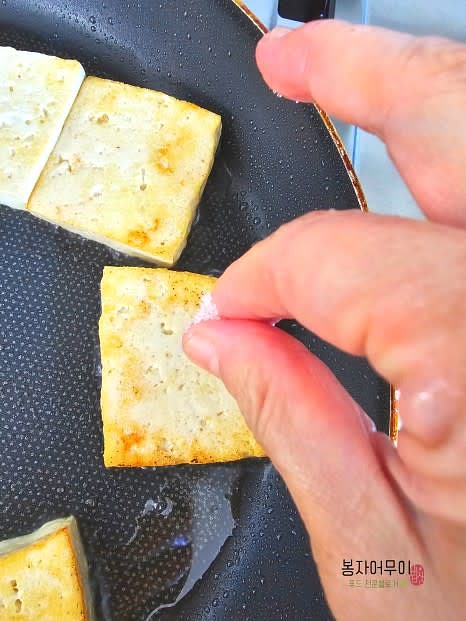 두부를 먹기 좋게 잘라 프라이팬에 올려 노릇노릇 구워줍니다. 구울 때 소금을 미리 뿌리면 두부의 수분이 더 잘 빠져나가고 맛이 깔끔해집니다.