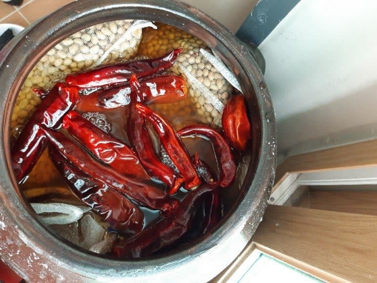 알메주를 소금물에 담그고 숙과 고추를 추가하여 발효를 촉진하고 잡내를 제거합니다.