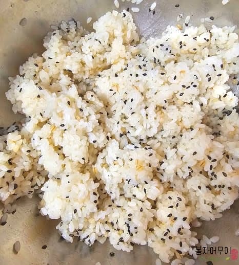 밥 한 공기에 단촛물을 만들어 섞고 참기름 1스푼과 흑임자를 넣어 잘 섞어줍니다.