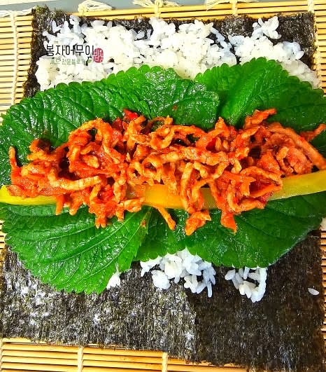 김밥용 김 위에 양념 밥을 얇게 펴고 단무지와 볶은 제육을 올립니다.