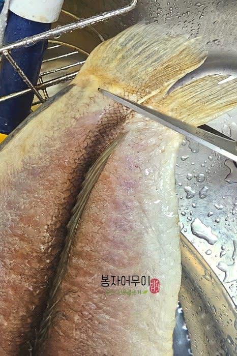 냉동 상태의 옥돔을 꺼내 칼로 등을 한 번 긁어주고, 지느러미 등을 잘라줍니다.
