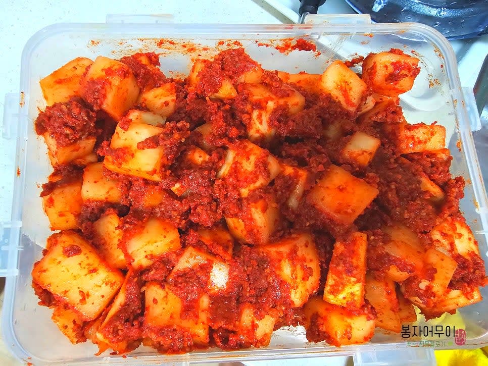 깍두기 양념에 물 빠진 무를 넣고 버무려서 통에 담아줍니다.